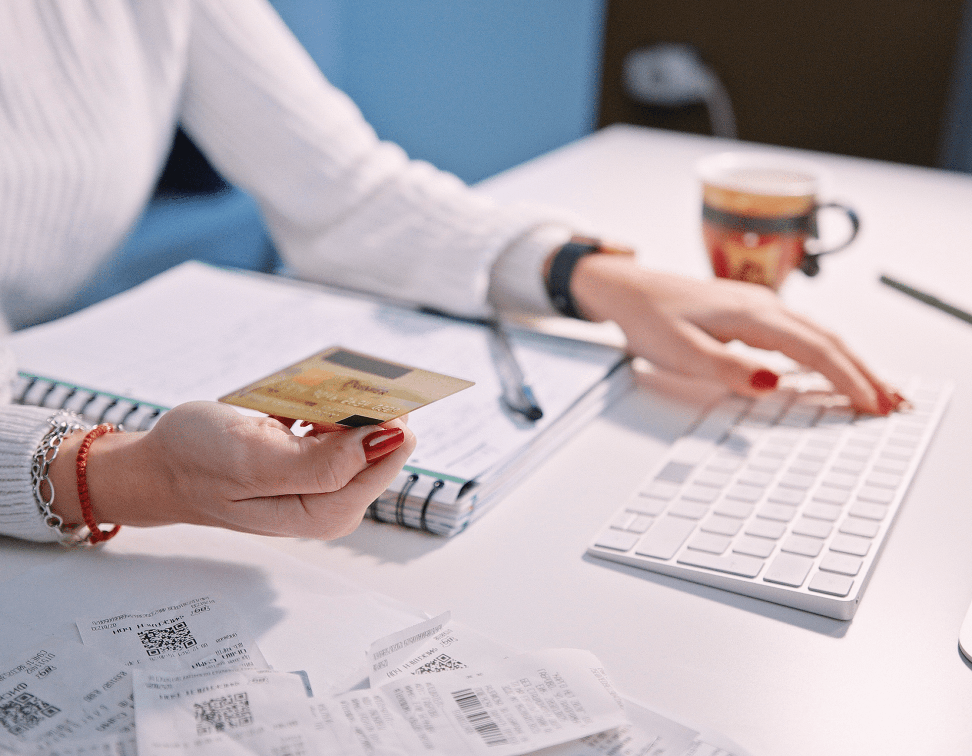 Person managing finances with credit card, receipts, and computer keyboard.