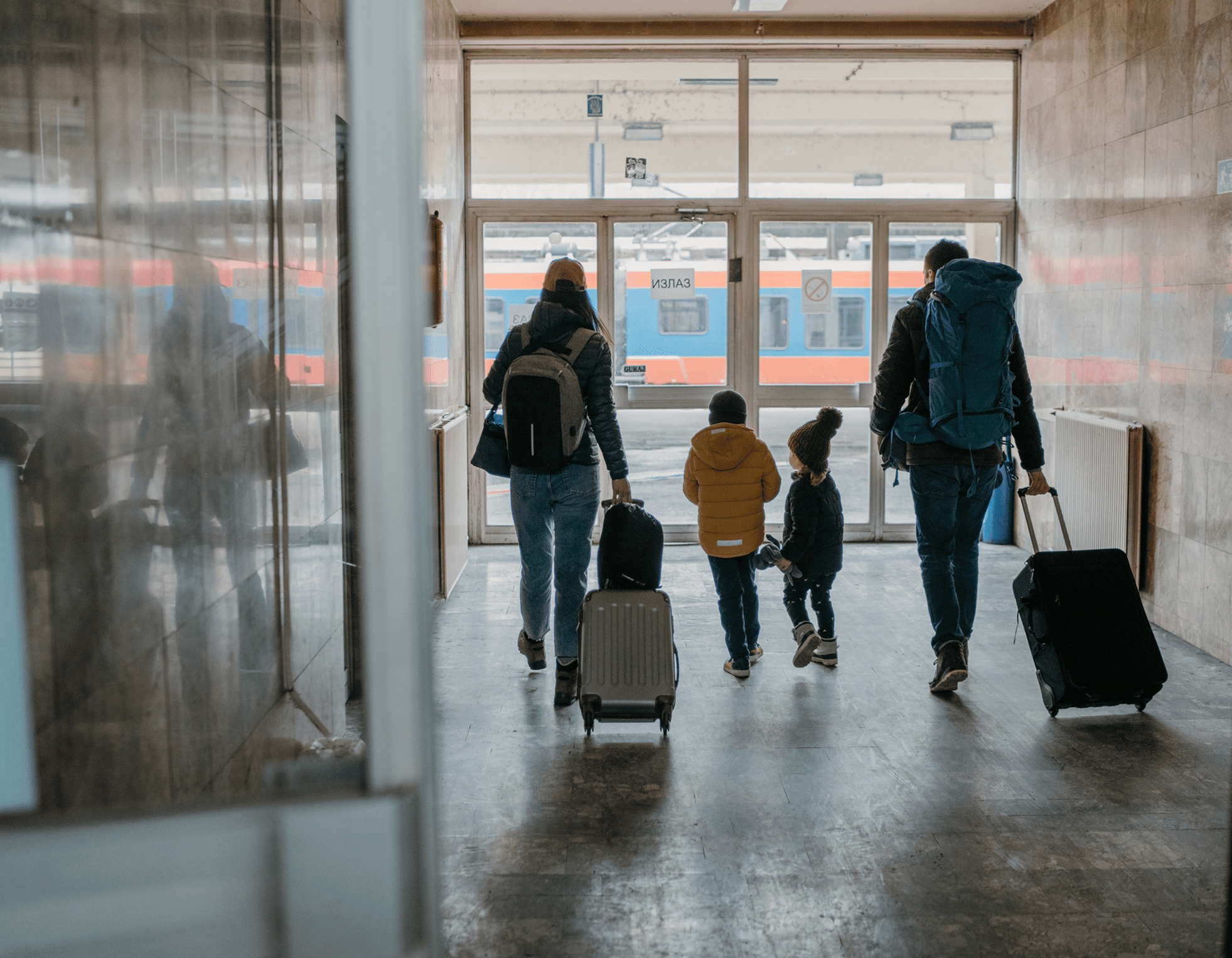 Travelers walking through an airport terminal with luggage.
