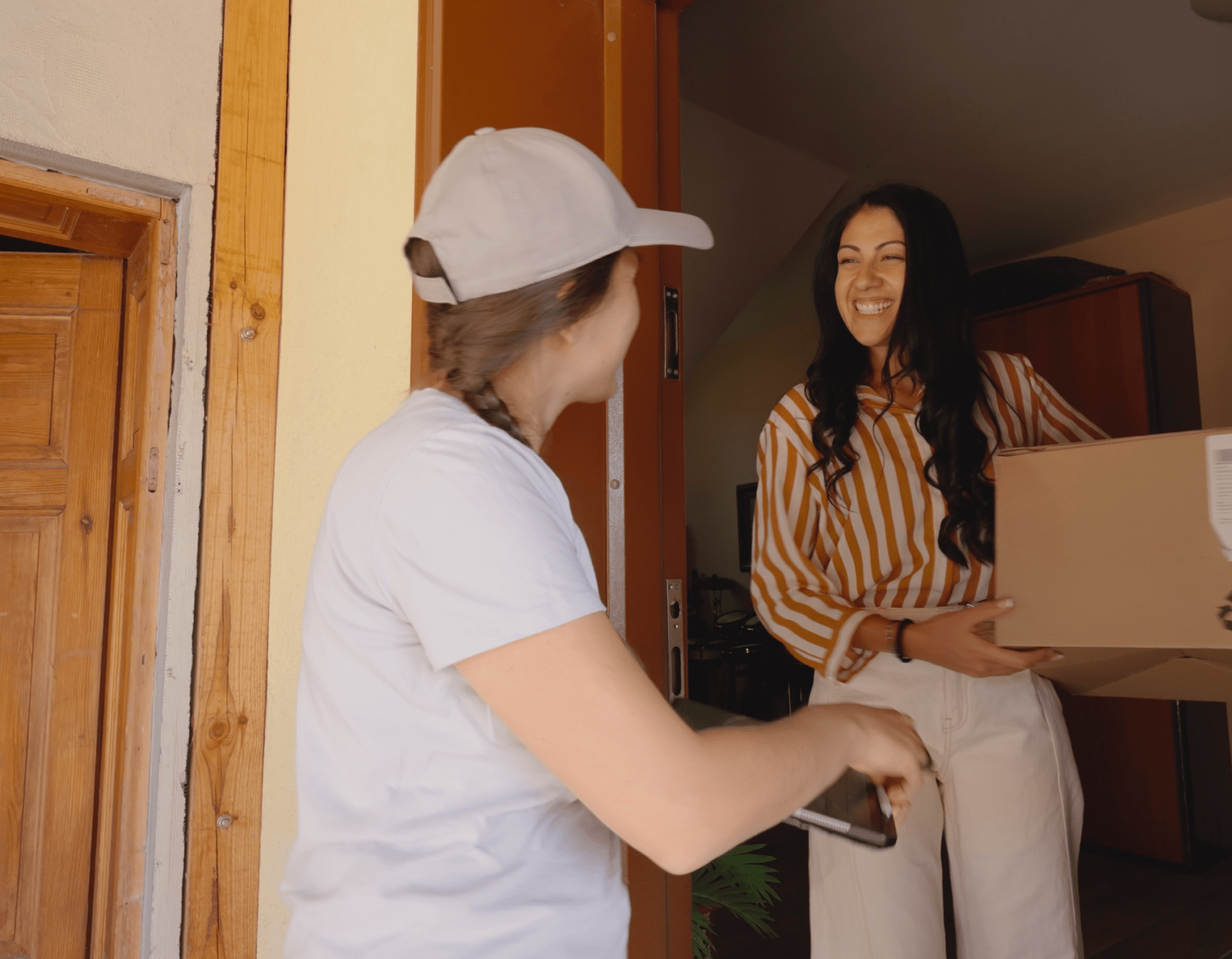 Two friends laughing and chatting at a doorway.